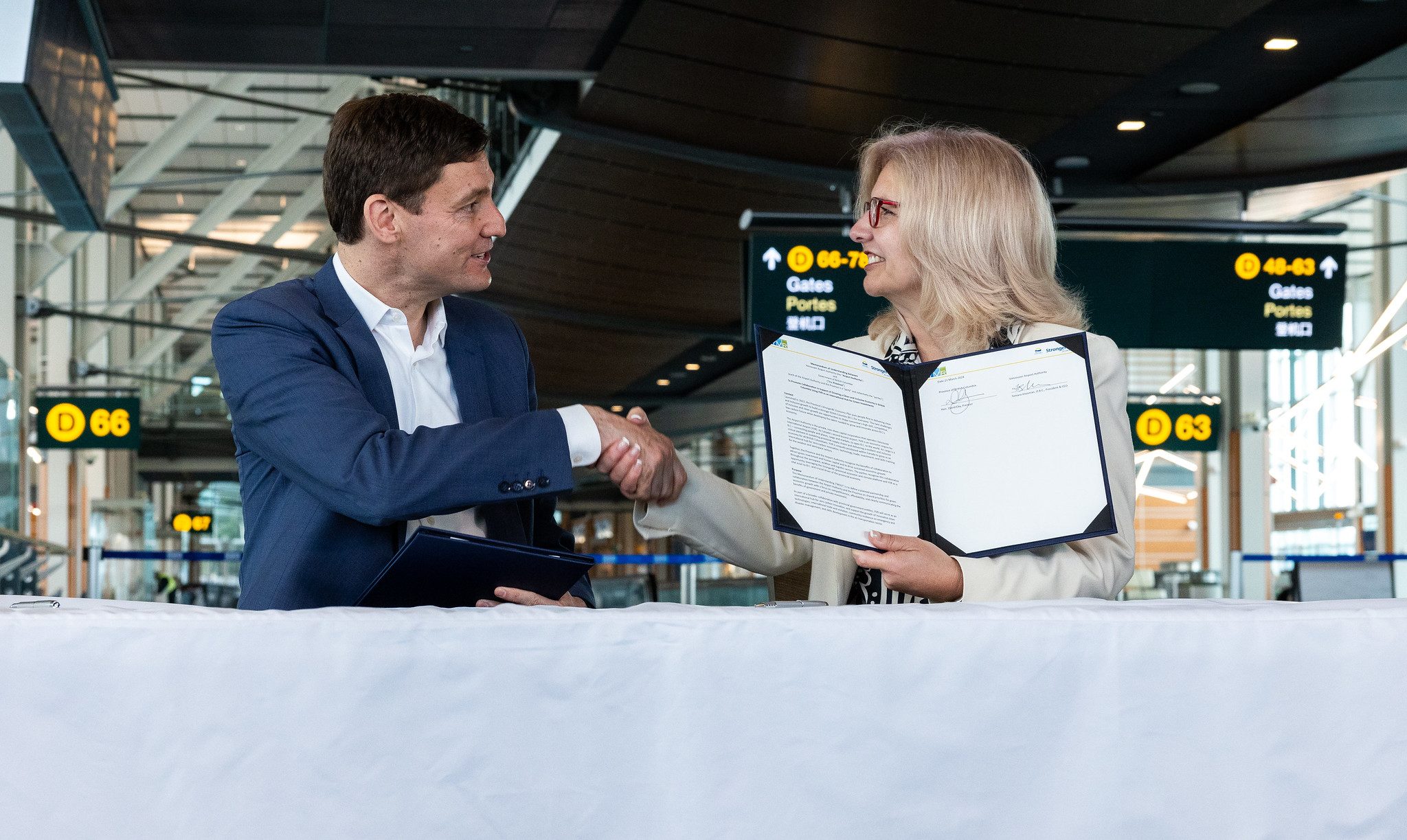 El primer ministro David Eby y la directora ejecutiva de YVR, Tamara Vrooman, se dan la mano.