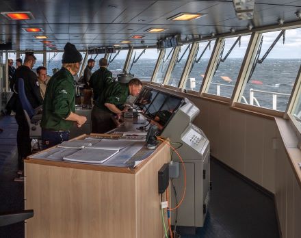 Trabajadores dentro de un barco frente a un sistema de navegación